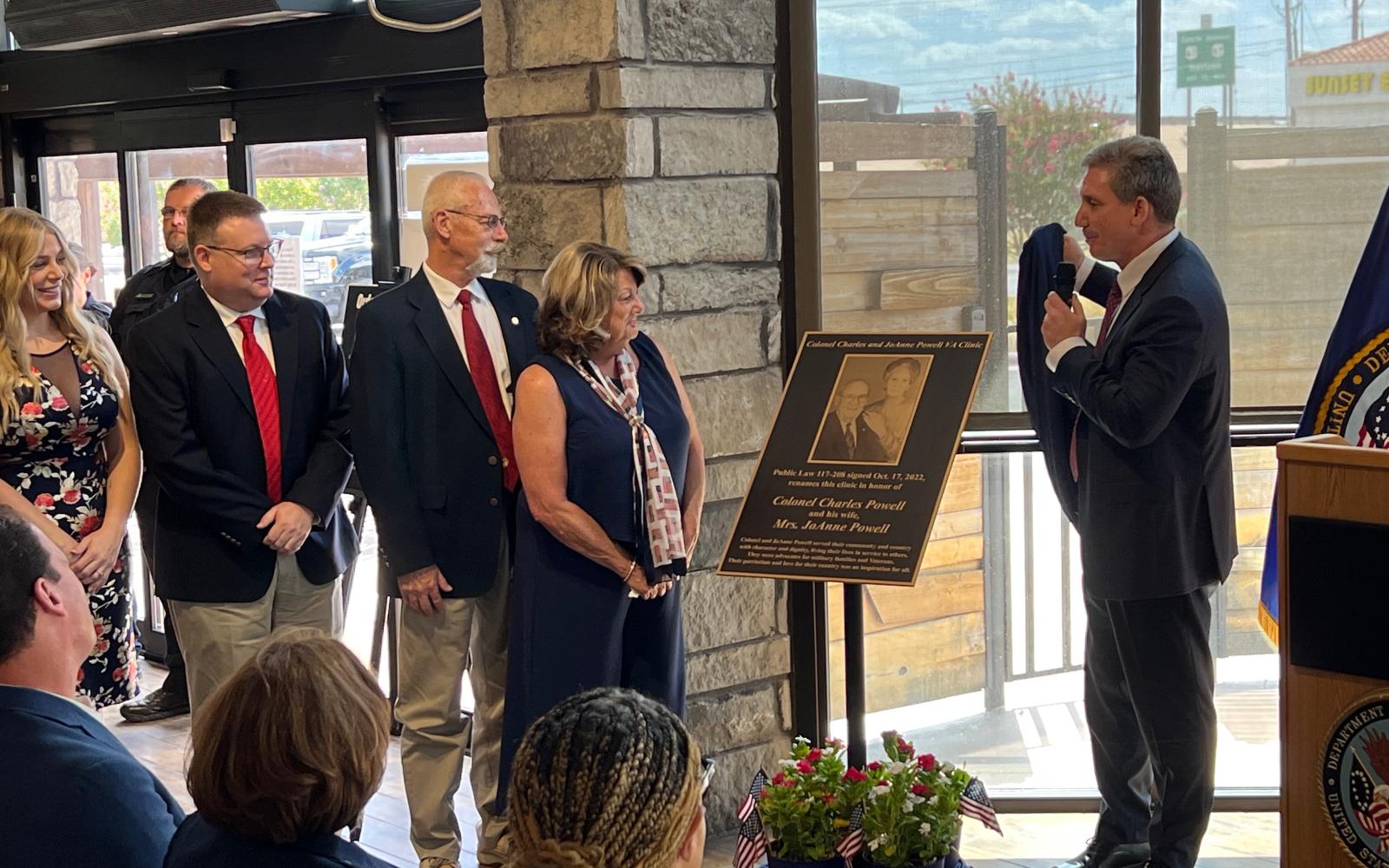 VA Director Keith Bass (right) unveils the plaque that will be affixed to the outside of the building in honor of Col. Charles and JoAnne Powell to the Powell's family. From left: Caitlin McKinney, Dr. Colin McKinney, Jerry and Terri McKinney.