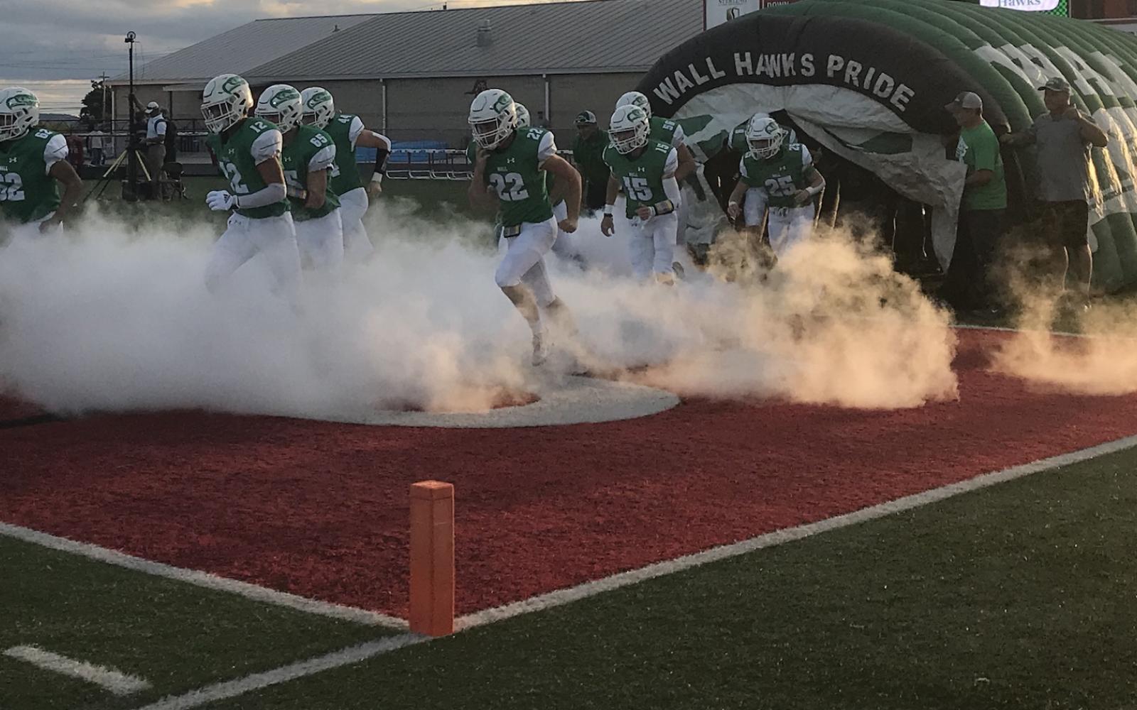 The Wall Hawks charge out of the tunnel before a game against Shiner in 2021.