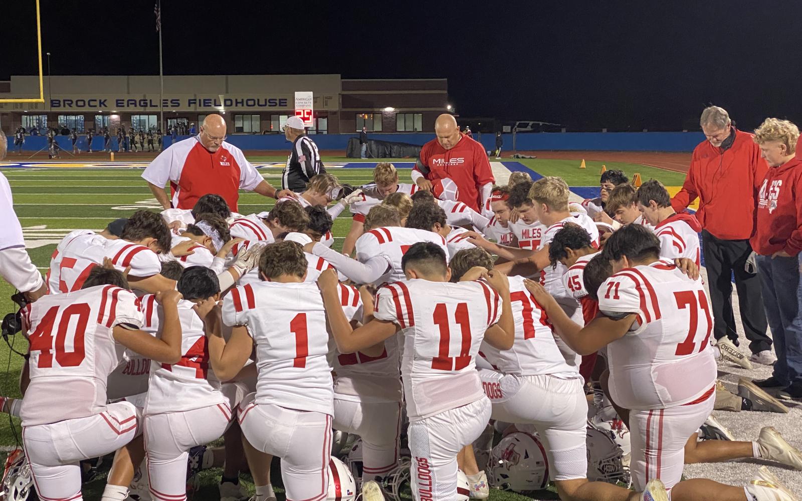 The Miles Bulldogs football team prays before its first-round playoff game against Lindsay in Brock on Thursday, Nov. 14, 2024.