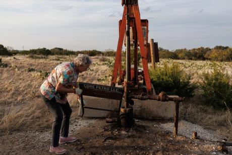 Jackie Chesnutt props up a sign next to a leaking oil well operated by CORE Petro on her property near Knickerbocker on Nov. 18, 2025.