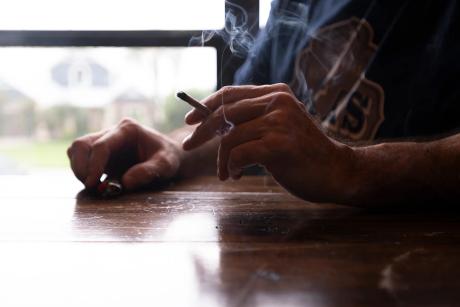 A man smokes a joint rolled from legal hemp flower in Onalaska on June 15, 2025.