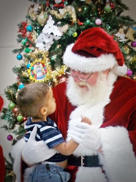 A little boy sits on Santa's lap at the Merry Little Christmas Party at Newbridge Family Shelter. (Photo courtesy of Sanford Mouton)