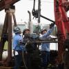 Oil workers pull tubing from an orphan well in a field in Luling on March 27, 2025